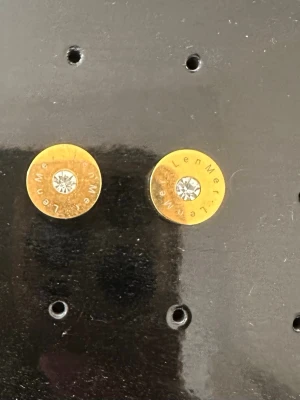 Guldtonade örhängen med kristall från LenMer - Snygga runda örhängen i guldtonad metall med en klar kristall i mitten. Runt kristallen finns ingraverad text. Perfekta för dig som gillar stilrena och eleganta accessoarer med en touch av bling. Aldrig använda, ordinarie pris 299kr! OBS: FRAKTAR INOM 24H!🩷