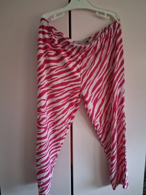 leggings 3kvarts - Snygga 3 kvarts leggings med rosa och vitt zebramönster. De har en bekväm resår i midjan och är tillverkade i ett stretchigt material som sitter skönt på kroppen. Perfekta för dig som vill sticka ut med ett djurmönster i din outfit.