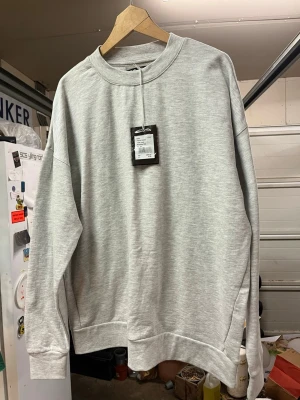 Ljusgrå basic oanvänd sweatshirt - En stilren oanvänd ljusgrå sweatshirt i klassisk modell med rund hals och ribbade muddar vid ärmslut och nederkant. Perfekt för en avslappnad look och enkel att matcha med det mesta. Tillverkad i mjukt material för extra komfort. Nypris 399kr