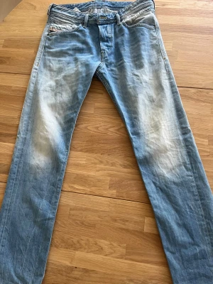 Ljusblå raka jeans med slitningar - Säljer ett par ljusblå jeans med raka ben och snygga slitningar på låren och knäna. Jeansen har klassisk femficksmodell och detaljer i kontrastsömmar. Materialet är mjuk denim i bomull. Perfekta för en avslappnad och trendig look.