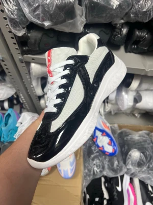 Svarta och vita sneakers  - Säljer ett par snygga sneakers från  i svart och vitt. Skorna har en blank svart detalj i lack, vit mesh på ovandelen och vita skosnören. Röd  syns både på plösen och hälen. Snygg och modern design som sticker ut.