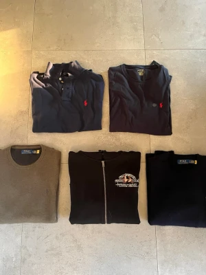 Ralph lauren paket - Säljer ett paket med Ralph lauren kläder. Allt är toppskick och oanvänt. Sakerna har bara legat i min garderob. Det förekommer en svart zip hoodie, en mörkblå long sleeve T-shirt och en mörkblå klassisk piké, en grön mesh-knit stickad tröja och en mörkblå wool stickad tröja. Allt är i storlek S, förutom den gröna tröjan som är i storlek M.