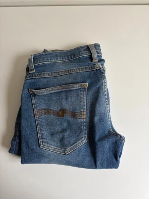 Nudie jeans - Jeans från nudie. Storlek 30/32. Snygga blå jeans i smal passform med klassisk femficksdesign och en unik söm på bakfickan. Jeansen har normal midja och är tillverkade i ett slitstarkt denimtyg. Perfekta för en avslappnad och trendig look.