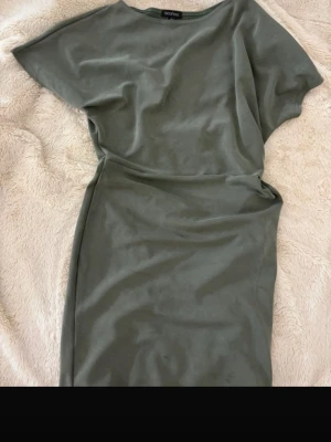 Grön enkel klänning från Boohoo - Snygg grön klänning från Boohoo med enkel och stilren design. Klänningen har korta ärmar och rak passform, perfekt för dig som gillar minimalistisk stil. Tillverkad i mjukt material som känns skönt mot huden.