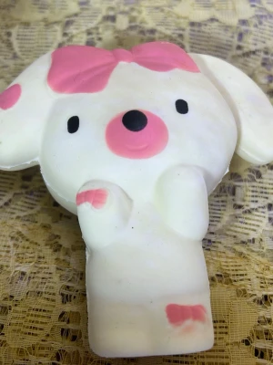 Söt squishy hund med rosa detaljer - En mjuk och klämvänlig squishy i form av en vit hund med stora öron, rosa rosett på huvudet och rosa detaljer på tass och fot. Perfekt som stressleksak eller dekoration. Tillverkad i mjukt skumgummimaterial.