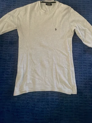 Vit långärmad tröja Polo Ralph Lauren - Säljer en vit långärmad tröja från Polo Ralph Lauren i 100% bomull. Tröjan har rund halsringning och den klassiska lilla logotypen broderad på bröstet. Perfekt för en clean och stilren look.