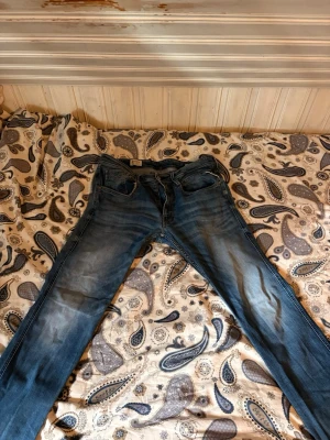Blå jeans från Replay - Säljer ett par klassiska blå jeans från Replay med. Jeansen har fem fickor, bälteshällor och dragkedja . Perfekta för dig som gillar en avslappnad men ändå stilren look.