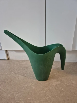 Vattenkanna - Säljer en grön vattenkanna i plast med modern, böjd design och lång smal pip. Perfekt för att vattna både krukväxter och blommor inomhus eller på balkongen. Lätt att bära tack vare det ergonomiska handtaget.