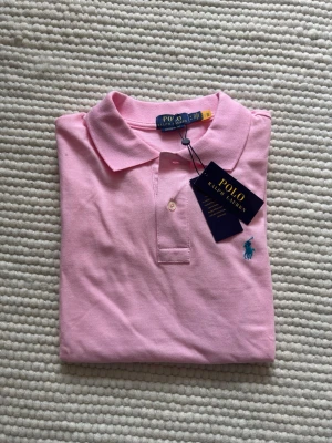 Rosa piké från Polo Ralph Lauren - Saljer en jatte fett rosa piké som ar perfekt för sommaren. Pikén är helt ny och endast testad, säljer pga fel storlek. Taggar och original påse medföljer vid köp Om ni har flera frågor eller funderingar är det bara att hojta!