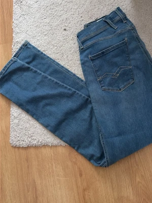 Blå raka jeans med bakficka  - Säljer ett par klassiska blå jeans med rak passform och snygg detaljsöm på bakfickan. Jeansen har normal midja och är tillverkade i ett slitstarkt denimtyg. Perfekta för en avslappnad och trendig look.