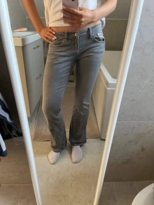bootcut jeans  - Säljer ett par gråa bootcut jeans med låg midja från Gina tricot. Korta på mig som är 175. Storlek 38 