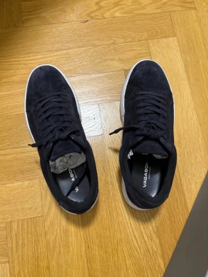 Navy vagabond skor - Stilrena baby sneakers från Vagabond i mjuk mocka med vita sulor. Klassisk låg modell med snörning och diskret logga på innersulan. Perfekta för dig som gillar en clean och tidlös look.