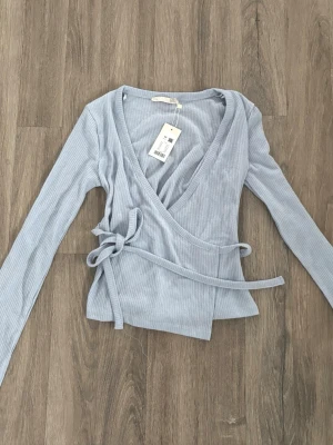 omlott topp lager  - ljusblå omlott tröja som man knyter från lager 157, stl xs och helt ny med prislapp kvar!🤍
