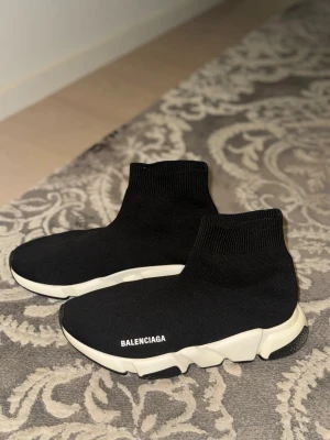 Balenciaga skor  - Svarta Balenciaga Speed Trainer sneakers med vit chunky sula och stickad ovandel i textil. Strumpliknande passform och logga på sidan. Perfekta för dig som gillar streetwear och vill ha en clean look.