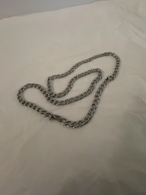 Kedjehalsband i silverfärg - Snyggt halsband med grova länkar i silverfärgad metall. Kedjan har en klassisk design som ger en cool och stilren look. Perfekt för att lyfta vilken outfit som helst med en edgy touch. Låset är diskret och smidigt.