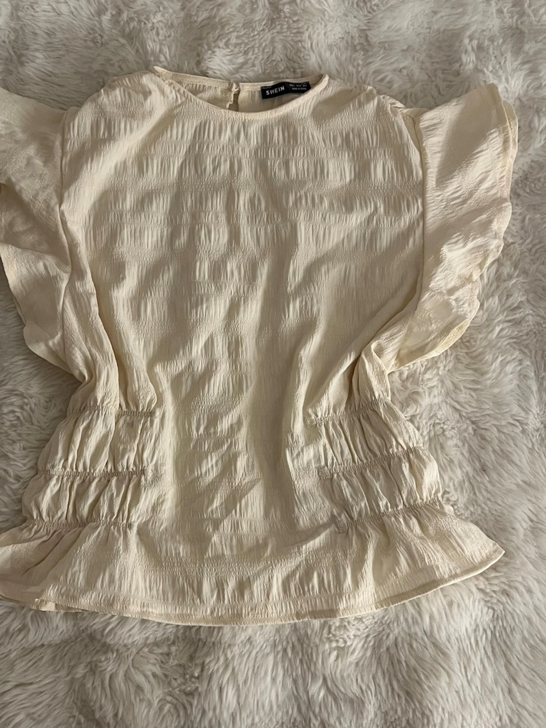 Vit blus med rynkdetaljer och volanger