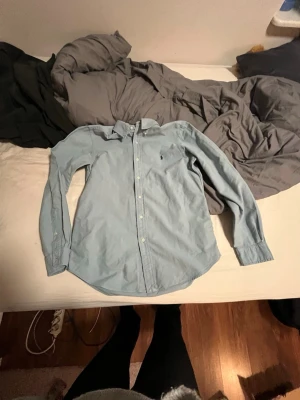 Ljusblå skjorta från Ralph Lauren - Klassisk ljusblå skjorta från Ralph Lauren med button-down krage och broderad logga på bröstet. Skjortan har långa ärmar, knappar framtill och är tillverkad i mjuk bomull. Perfekt för en clean och stilren look.