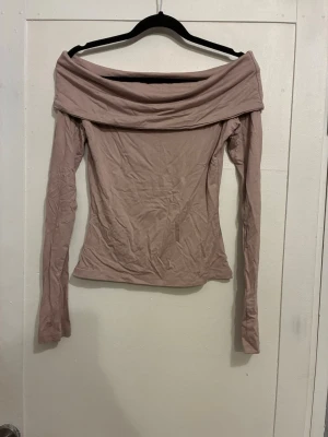 Superfin offshoulder topp - Trendig offshoulder topp med långa ärmar och bred krage som vilar över axlarna. Tunn och mjuk i materialet, perfekt för att styla med jeans eller kjol. Enkel och stilren design. Helt ny.