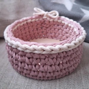 Handvirkad rosa förvaringskorg - Superfin rund förvaringskorg som är handvirkad i ljusrosa garn med vit kant och en liten rosett. Korgen har en stadig botten i trä och passar perfekt för småprylar, smink eller dekoration. Materialet är tjockt garn som ger en mysig och modern känsla.