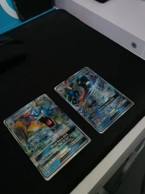 Pokémonkort Gyarados GX och Kingdra GX - Två Pokémonkort: Gyarados GX och Kingdra GX. Båda korten har holografisk yta med blå och färgstarka illustrationer. Perfekta för samlare eller Pokémon TCG-spelare. Kortens baksida har klassiskt blått Pokémon-motiv med Pokéboll.