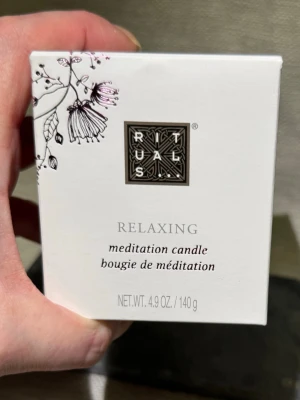 Nytt! Rituals Sakura Relaxing meditationsljus - Helt nytt! 140gr. Säljer ett vitt meditationsljus från Rituals i en stilren glasbehållare. Ljusets doft är framtagen för att skapa en avslappnande atmosfär och förpackningen har ett elegant blommönster. Perfekt för meditation eller lugna stunder hemma.