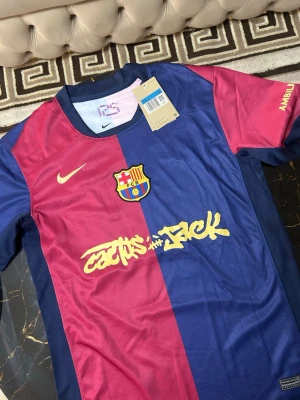 FC Barcelona matchtröja Nike - Säljer en FC Barcelona matchtröja från Nike med Lamine Yamal och nummer 19 på ryggen. Tröjan är kortärmad och har klassiska blå och röda paneler med gula detaljer och klubbmärke på bröstet. Tillverkad i lätt polyester, perfekt för fotbollsträning.