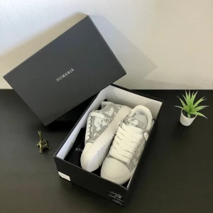 Gråvita sneakers från Numeris - Snygga sneakers från Numeris i grått och vitt med coolt camo-mönster. Skorna har vita snören, grov sula och är tillverkade i textil och syntetmaterial. Perfekta för dig som vill sticka ut med en unik stil.