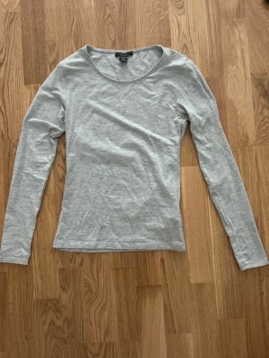 Ljusgrå långärmad topp från Amisu - En basic ljusgrå långärmad topp från Amisu med rund halsringning. Tillverkad i mjuk bomullsmix, perfekt att styla med jeans eller kjol. Enkel och stilren design som funkar till många olika looks.