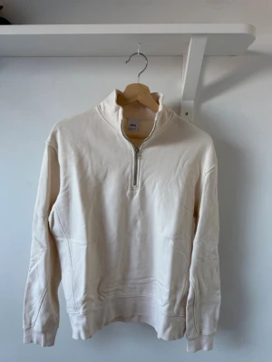 Vit halvzip hoodie från Zara - Snygg vit hoodie från Zara med halvzip framtill och hög krage. Tillverkad i mjukt bomullsmaterial. Perfekt för en clean och stilren look.