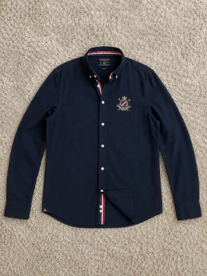 Morris Gents Skjorta - Säljer en riktigt snygg Morris skjorta i mörkblå färg med fina detaljer, perfekt om man gillar en lite mer uppklätt.  Klassisk design med broderad Morris detalj på bröstet samt snygga kontrastdetaljer i kragen och knappslån som gör att den sticker ut på ett stilrent sätt.  Fint skick. Mörkblå färg, enkel att matcha med det mesta.  Storlek: S Passform: Regular Fit  Pris kan diskuteras vid snabb affär. Bara att skriva vid frågor eller om du vill ha fler bilder!