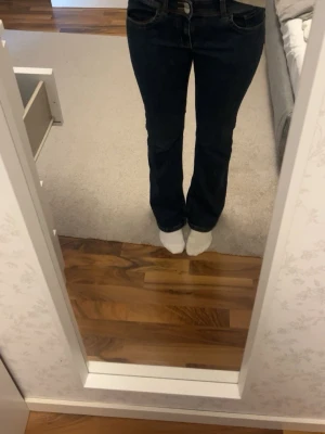 Mörkblå bootcut jeans - Snygga mörkblå bootcut jeans med klassiska gula sömmar och femficksdesign. Jeansen har en normalhög midja och lätt utsvängda ben. Perfekta för dig som gillar en tidlös och stilren look. De passar mig som brukar ha 38 i jeans 💗