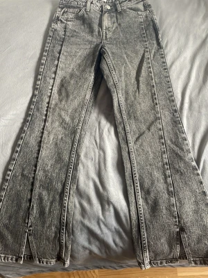 Gråa bootcut jeans med slits - Snygga grå bootcut jeans från C Denim med cool tvättad look och slitsar längst ner på benen. Klassisk femficksmodell och knappstängning. Perfekta för dig som gillar en trendig och avslappnad stil.