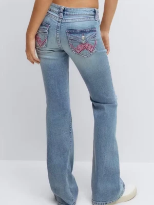 Ljusblå bootcut jeans med broderi - Ljusblå bootcut jeans med slitna detaljer framtill och broderade bakfickor i rosa. Låg midja och klassisk femficksmodell. Jeansen har en avslappnad passform och är tillverkade i denim med lätt stretch. Använt typ en gång är för små 