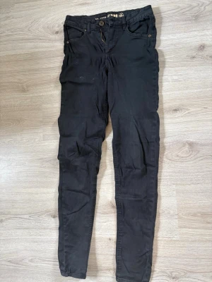 Svarta skinny jeans från Stella - Säljer ett par svarta skinny jeans från Stella med klassisk femficksdesign och knappgylf. Jeansen har smal passform och är tillverkade i stretchigt material för en bekväm känsla. Perfekta till en avslappnad och trendig stil.