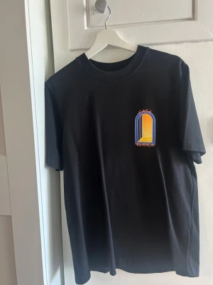 Svart Casablanca t-shirt med tryck - Snygg svart t-shirt från Casa Blanca med färgglatt grafiskt tryck i blått, gult och orange både fram och bak. Klassisk passform och rund halsringning. Perfekt för dig som gillar streetwear och vill sticka ut lite extra.