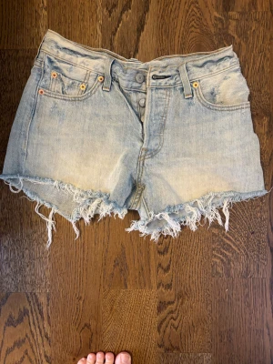 Ljusblå jeansshorts från Levi's storlek 25 - Supersnygga Levi’s jeansshorts i ljus tvätt med perfekt vintagekänsla ☀️ Högmidjad modell med råfransad kant och klassisk Levi’s-passform. Väldigt smickrande och perfekta till sommarens linne, skjorta eller bikini.  Storlek: 25 Färg: Ljusblå denim Skick: Fint använt skick