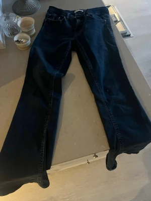 Mörkblå bootcut jeans från Gina Tricot - Säljer ett par mörkblå bootcut jeans från Gina Tricot. Jeansen har klassisk femficksmodell, hög midja och vida ben med slits nertill. Tillverkade i stretchigt denimtyg för skön passform. Perfekta för en trendig och avslappnad look.
