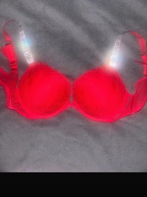 Victoria Secret bh - Snygg röd push-up bh med spetsdetaljer och vadderade kupor. Glitter band som de står ”Victoria Secret” såklart äkta 
