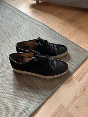 Svarta sneakers från Lanvin - Svarta sneakers från Lanvin med vit sula och klassisk snörning. Skorna har en stilren design med rund tå och är tillverkade i skinn. Perfekta för dig som gillar en clean och tidlös look.