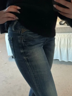 Mörkblå jeans från Replay - Snygga mörkblå vintage jeans från Replay med klassisk femficksdesign och diskreta slitningar. Jeansen har en smal passform och detaljerad bakficka med broderi. Perfekta för en trendig och avslappnad look.