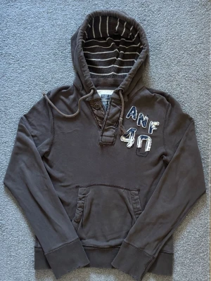 Vintage Abercrombie & Fitch Hoodie - As Snygg vintage  grå hoodie från Abercrombie & Fitch med broderad logga och text på bröstet. | Storlek S | Längd 67cm , Bredd Armhåla - Amrhåla 50cm | Mycket fint skick | Pris kan diskuteras! Modell 175 cm, 68kg