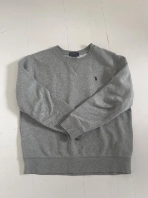 Grå sweatshirt från Polo Ralph Lauren - Klassisk grå sweatshirt från Polo Ralph Lauren med rund halsringning och broderad marinblå logga på bröstet. Nypris:-1195kr.