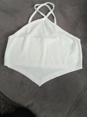 Vit ärmlös linnetopp med smala band - Aldrig använd. Säljer en vit linnetopp med smala axelband. Toppen har en spetsig nederkant och är tillverkad i ett mjukt frottéliknande material. Perfekt för sommardagar och enkel att matcha med jeans eller kjol.