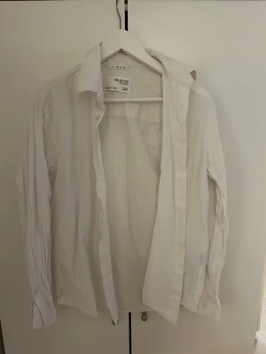 Vit linneskjorta från Selected Homme - Klassisk vit skjorta i linne från Selected Homme. Skjortan har lång ärm, knappar framtill och en avslappnad passform. Perfekt för en stilren och enkel look. Materialet är luftigt linne som passar bra till varmare dagar.