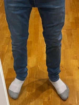 Replay jeans - Ljusblå jeans från Replay, modell Anbass, i storlek W31 L32. Jeansen är i mycket bra skick, förutom en liten slitning vid grenen som kan tolkas som en detalj. Personen på bilden är cirka 180 cm som referens för passformen. Nypris ligger på 1500 kr. Måtten är: midjemått 40 cm och längd 100 cm.  Kolla gärna in profilen också, där finns flera märkeskläder och skor – du hittar säkert något mer som passar 😉💯 Hör av dig om du undrar något!