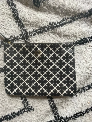 Svartvit kuvertväska från by malene birger - Snygg kuvertväska från by malene birger i svart och vitt med ett grafiskt mönster. Väskan har guldfärgad dragkedja och rund logga framtill. Tillverkad i ett tåligt konstläder som känns lyxigt och trendigt.💕 