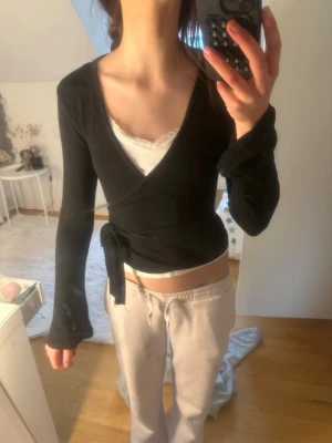 Svart omlottopp med knyt - Svart omlottopp tröja från ginatricot. 