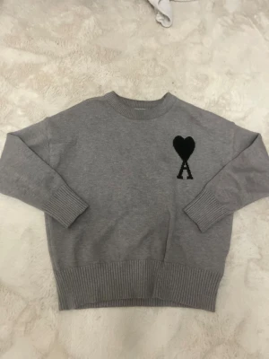 Ami Paris tröja - Fin Ami Paris sweatshirt Grå i storlek S. Bekväm passform och mjukt material, med det ikoniska hjärtloggan. I topp skick utan fläckar eller hål.