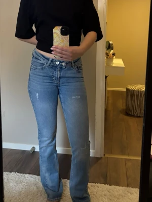 Ljusblå bootcut jeans - Säljer ett par ljusblå bootcut jeans med lätt slitna detaljer ifrån junkyards i storlek xs. Lågmidjade.😍😗