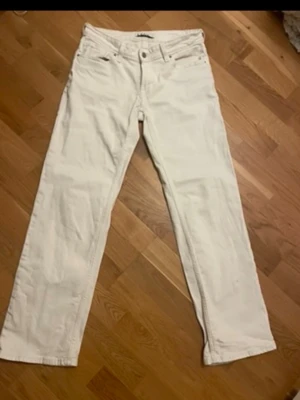 Vita raka jeans från Stay - Säljer ett par vita jeans från Stay med rak passform och klassisk femficksdesign. Jeansen har normal midja och är tillverkade i ett mjukt bomullsmaterial med lite stretch. Perfekta för en clean och fräsch look.